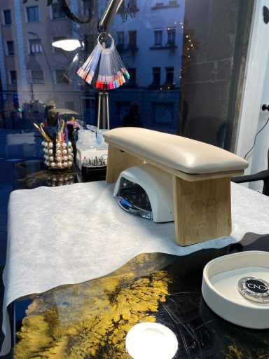 Mesa de manicura con lámpara UV, herramientas y una ventana al fondo.